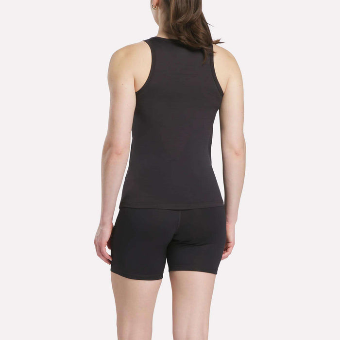 A woman faces away from the camera, wearing a Reebok Women's Marled Performance Tank Top and black shorts against a plain light background.