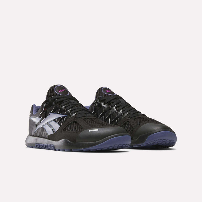 The Women's Nano 2.0 Training Shoes by Reebok feature a black design with silver accents, purple details, and textured soles for functional fitness, shown against a plain white background.
