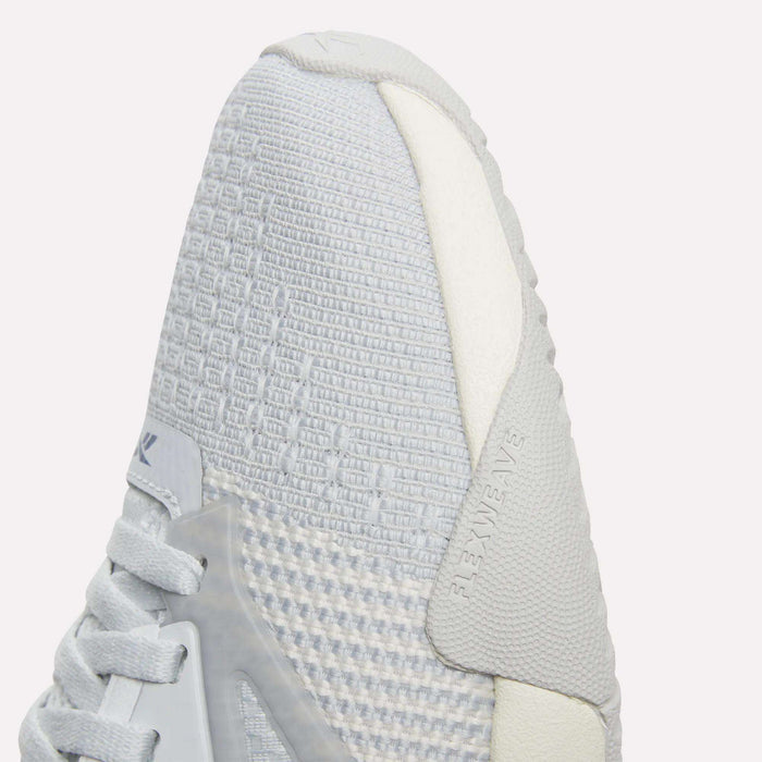 Close-up of the toe on a light gray and white Reebok Women’s Nano Court Training Shoe, featuring textured mesh, white laces, a smooth side overlay, and a durable Griptonite rubber outsole for court sports.