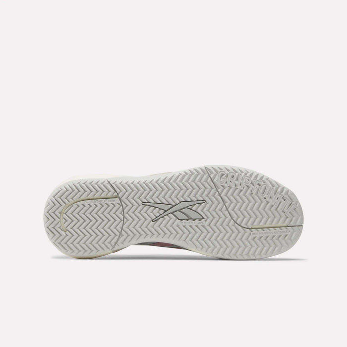 The image displays the white Griptonite rubber outsole of the Women's Nano Court Training Shoes by Reebok, featuring a herringbone tread pattern. The Reebok logo is centered, and "GRIPTON" is embossed near the heel.