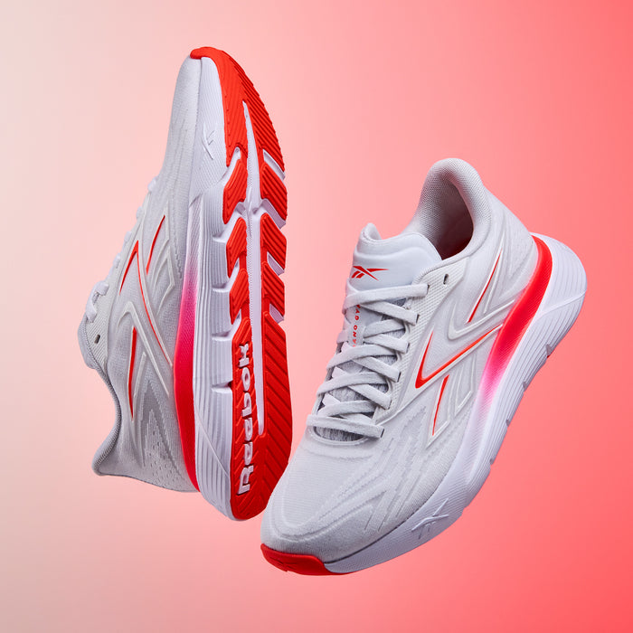 White and red Nano Gym 2.0 training and running shoes with 'Reebok' branding on a gradient pink background