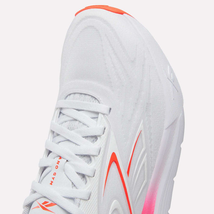 Close-up of the Reebok Women's Nano Gym 2.0 Training Shoes in white, with red and orange accents, a textured upper, white laces, cushioned sole with pink at the midsole—perfect for training.