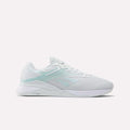 The Reebok Women's Nano X4 Training Shoes are white athletic sneakers with light blue accents, breathable mesh fabric, the Reebok logo on the side, and a flat supportive sole with Floatride Energy Foam for sports or casual use.