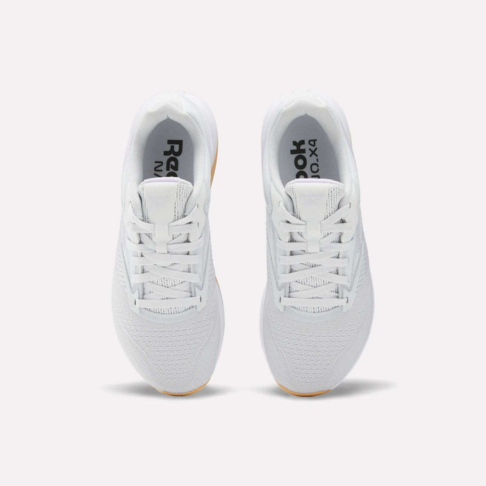 A top view of Reebok Women's Nano X4 Training Shoes in white with light brown soles, featuring a breathable design and Floatride Energy Foam, shown side by side on a plain white background.