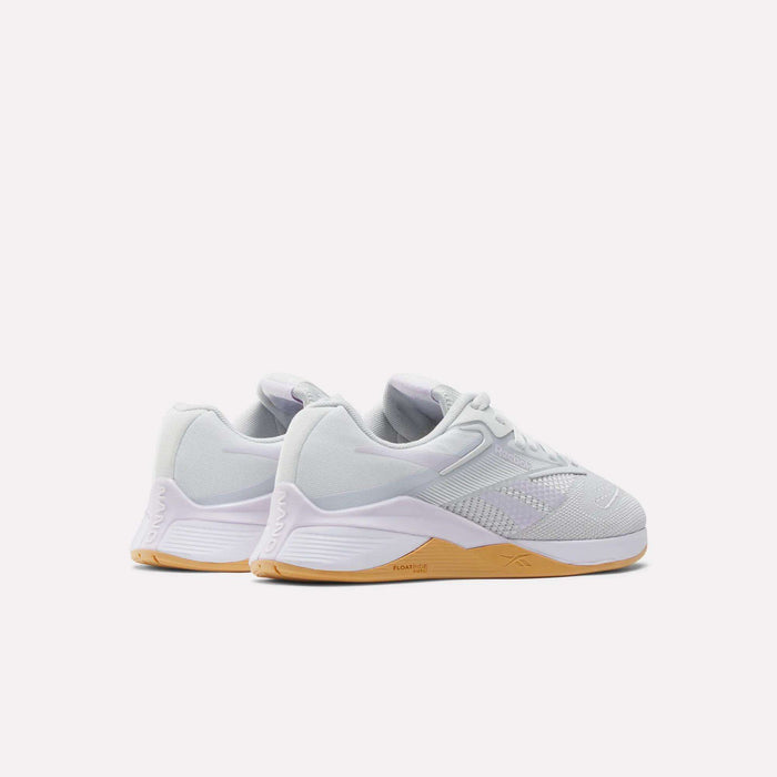 A pair of Reebok Women's Nano X4 Training Shoes in white with light brown rubber soles, breathable uppers, and supportive Floatride Energy Foam, shown from the side and slightly behind on a plain white background.