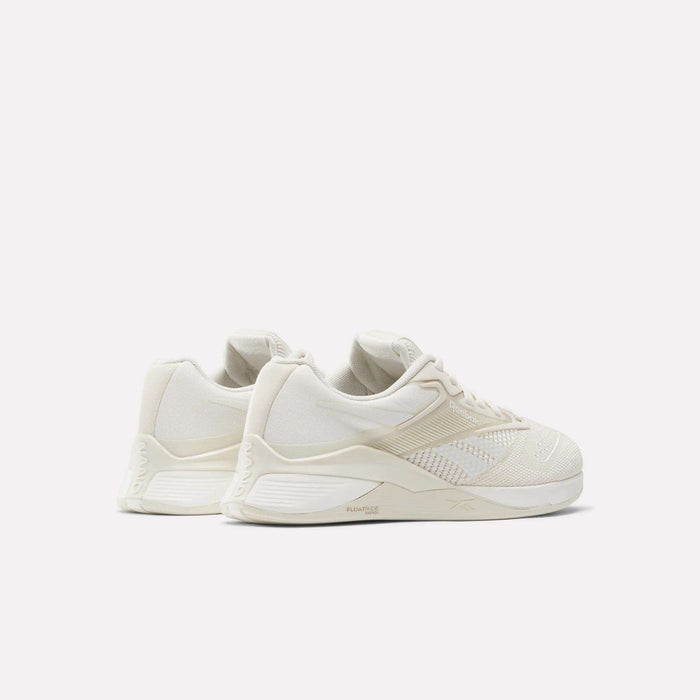 The Women's Nano X4 Training Shoes by Reebok are off-white with textured details, a Flexweave upper, low-top design, and chunky soles, displayed against a plain white background.