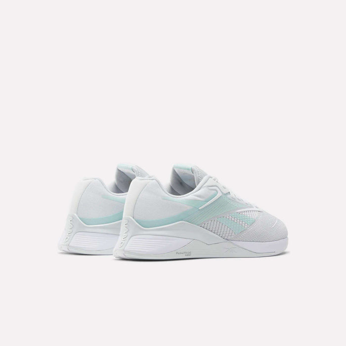 A pair of Reebok Women's Nano X4 Training Shoes in white and pale mint green with Floatride Energy Foam are shown side by side on a light background, displaying their sides and backs.