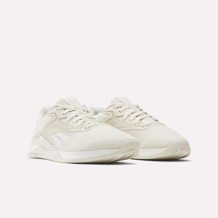 A pair of Women's Nano X4 Training Shoes by Reebok, in off-white with mesh and synthetic Flexweave uppers, laced and placed side by side on a plain white background.