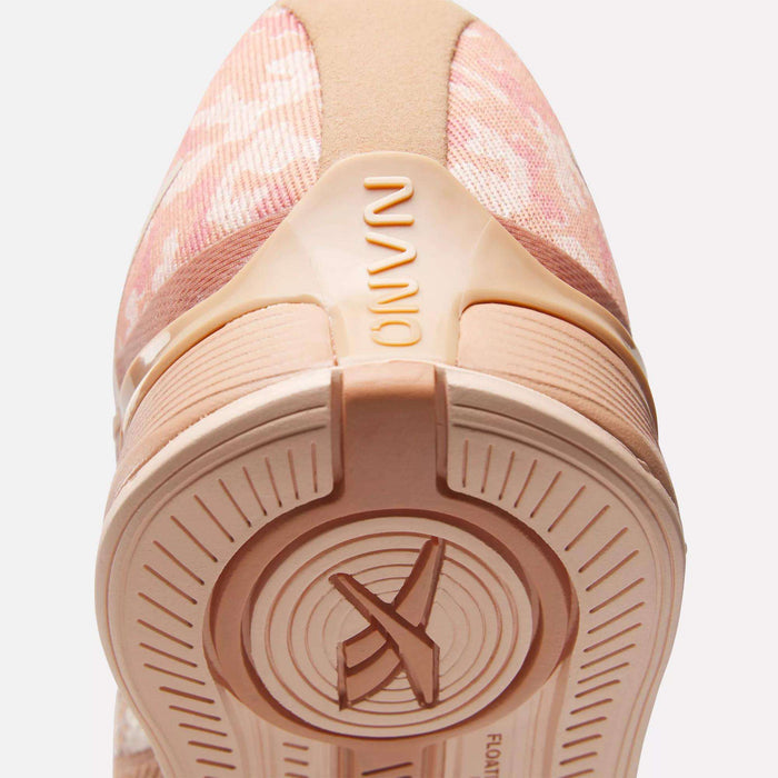 Close-up of the heel and sole of Reebok Women's Nano X4 Training Shoes in pink with beige accents. "NANO" appears on the heel, and the lightweight, breathable sole features circular patterns with an X design at the center.