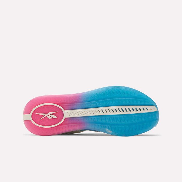 The image shows the sole of Reebok Women's Nano X4 Training Shoes, with a pink-to-blue gradient design and white Reebok logo on the heel. Textured, vented patterns showcase these lightweight training shoes.