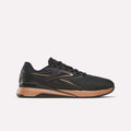 The Reebok Women's Nano X5 Edge Training Shoe in black with copper and brown accents is shown from the side on a white background, featuring copper details on the sole and heel, plus visible Reebok logos.