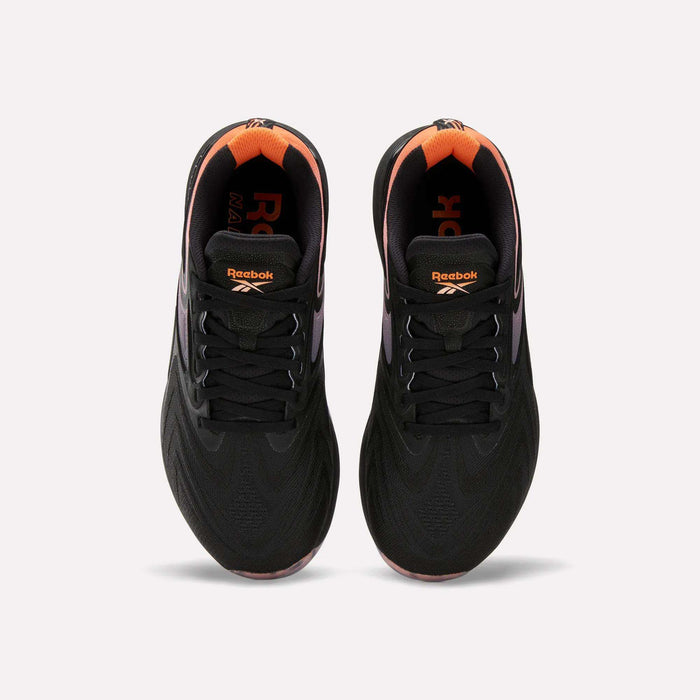 Top view of Women's Nano X5 Edge Training Shoes by Reebok in black with orange heel and inner accents, Reebok logo on tongue and insole. Shoes shown side by side on a white background.