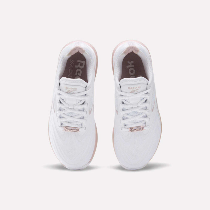The Reebok Women's Nano X5 Edge Training Shoes feature a white upper, white laces, and a light pink sole. The Reebok logo appears on the insoles and tongue, combining style and performance—ideal for HIIT workouts.