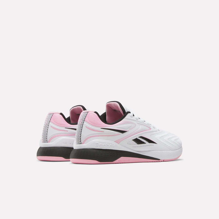The Reebok Women's Nano X5 Edge Training Shoes feature a white upper with black and light pink accents plus a black sole with pink details, displayed at an angle to show both the back and side views.
