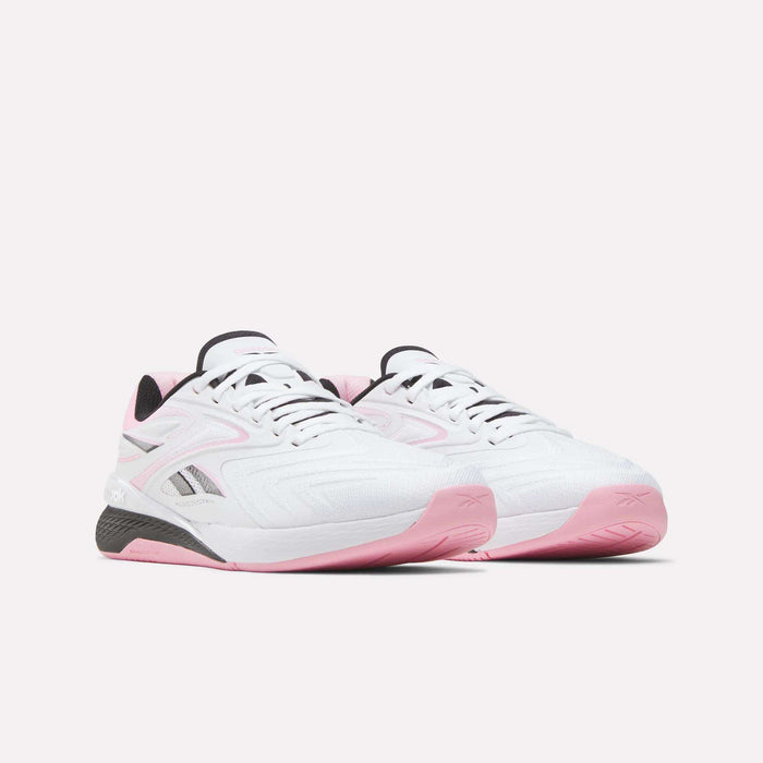 A pair of Reebok Women's Nano X5 Edge Training Shoes in white with pink accents and black detailing, featuring a subtle Reebok logo on the side, displayed against a plain light background.