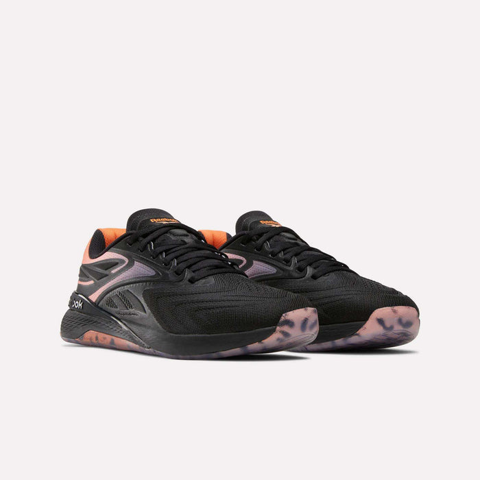 Women's Reebok Nano X5 Edge Training Shoes in black with orange accents, featuring mesh uppers and patterned translucent rubber soles, shown against a plain light background.