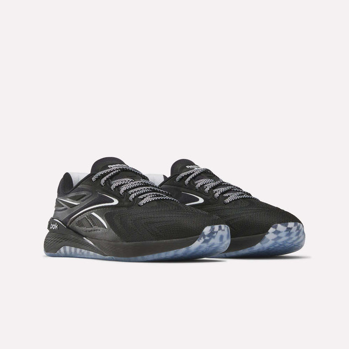 A pair of Reebok Women's Nano X5 Edge Training Shoes in black with white and gray accents, patterned laces, and translucent blue-gray soles, displayed on a plain white background.