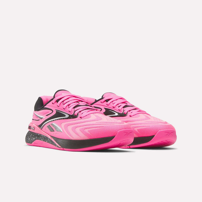 The Women's Nano X5 Edge Training Shoes by Reebok feature a bright pink design with black and silver accents, a textured sole, and modern style—ideal for HIIT—shown on a plain white background.