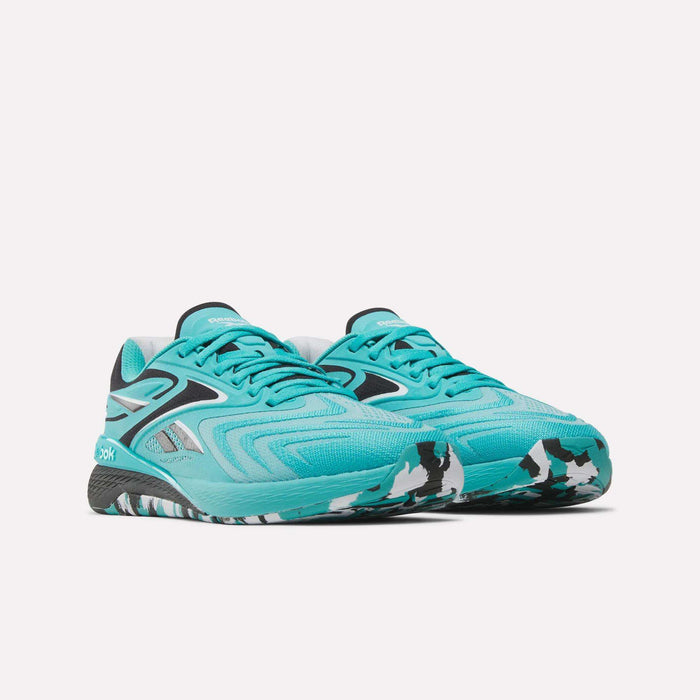 A pair of Reebok Women’s Nano X5 Edge Training Shoes in teal, featuring black and white patterned soles and black accents, are positioned side by side on a plain white background.