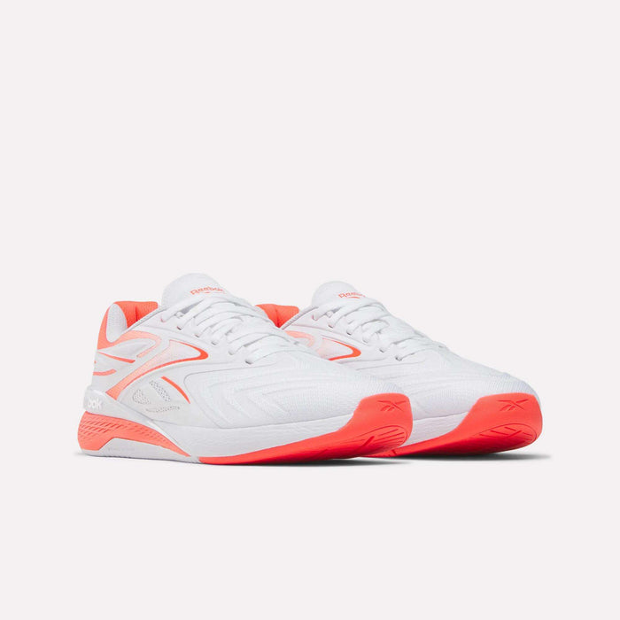 A pair of Reebok Women's Nano X5 Edge Training Shoes in white with bright coral accents and soles are displayed on a plain light background, facing slightly right.