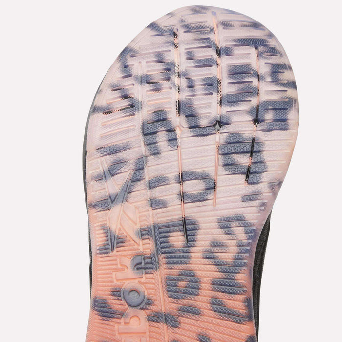 Close-up of the translucent outsole on the Reebok Women's Nano X5 Edge Training Shoes, showing bold black leopard spots over a pink-orange gradient, with grooves and embossed details visible.