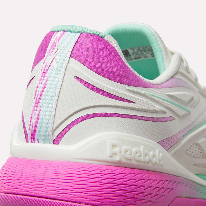Close-up of the heel on Reebok Women's Nano X5 Edge Training Shoes in white, pink, and teal. Features an embossed Reebok logo, gradient pink sole, and purple accents—ideal for your next HIIT class.