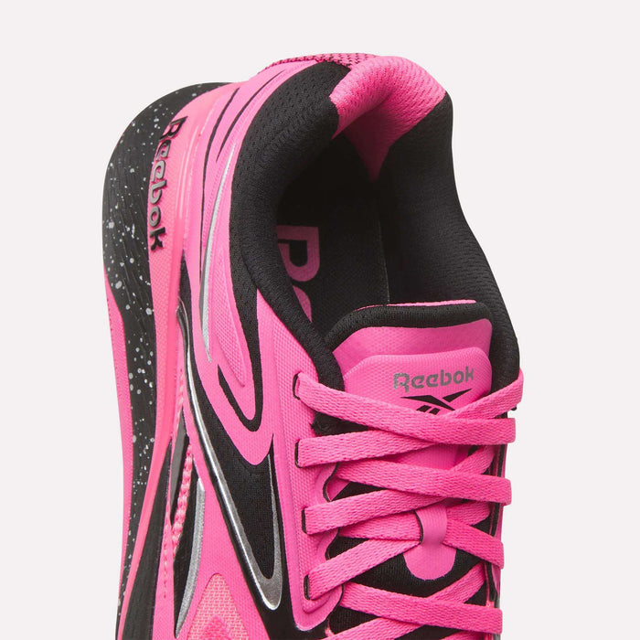 Close-up of Reebok Women's Nano X5 Edge Training Shoes in bright pink and black, featuring pink laces, black lining, and a white speckled sole. The Reebok logo appears on the tongue and inner heel—ideal for your next HIIT class.