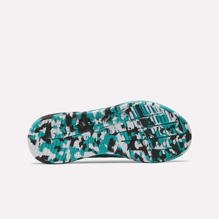 The image displays the sole of the Reebok Women’s Nano X5 Edge Training Shoes, showcasing a teal, black, and white camouflage pattern with textured grooves and tread for enhanced traction—an ideal design for women’s workout footwear.
