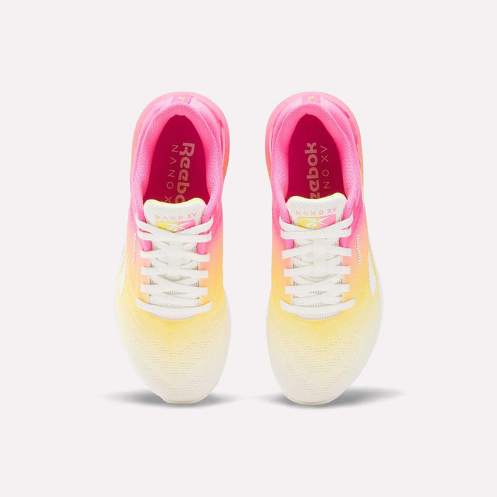 A pair of Reebok Women's Nano X5 Training Shoes shown from above, with a gradient design fading from pink at the heel to yellow midfoot and white at the toe, white laces, and Reebok branding on the insoles.