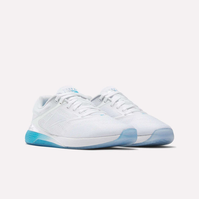 The Women's Nano X5 Training Shoes by Reebok feature a white design with light blue accents and semi-transparent blue soles, shown against a plain white background.
