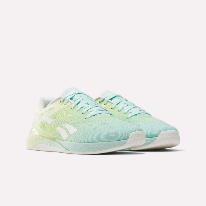 A pair of Reebok Women's Nano X5 Training Shoes in light blue and pastel green with white soles and white Reebok logos, shown on a plain white background.