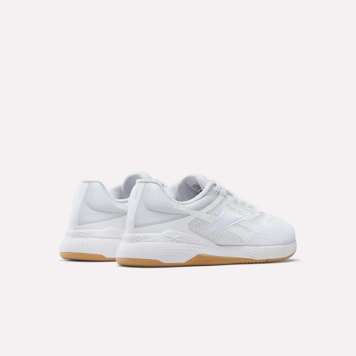 The Reebok Women's Nano X5 Training Shoes are white athletic sneakers with mesh uppers, white laces, and light brown rubber soles. Displayed against a plain background, both the heel and side views highlight their comfortable design.