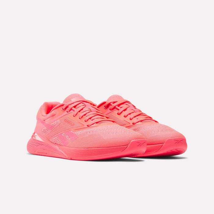 A pair of Reebok Women's Nano X5 Training Shoes in bright pink, featuring mesh uppers and rubber soles, displayed side by side on a plain white background.