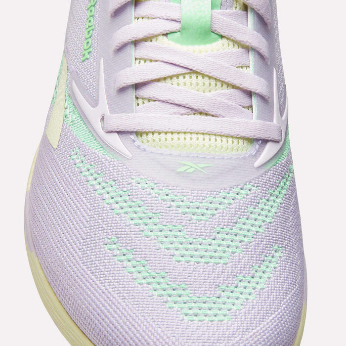 Close-up of Reebok Women's Nano X5 Training Shoes in pastel purple with mint green accents and white laces. Mesh material and detailed stitching on the toe and upper ensure comfort, ideal for running or training.