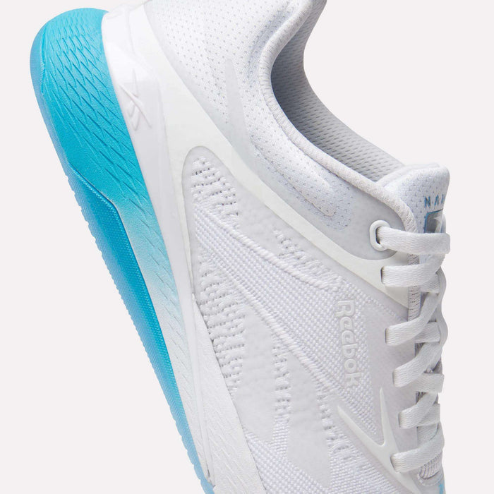 A close-up of the Reebok Women's Nano X5 Training Shoes, featuring a textured bright blue sole and white laces, shown from the side against a plain white background—ideal for those seeking stylish women's training footwear.