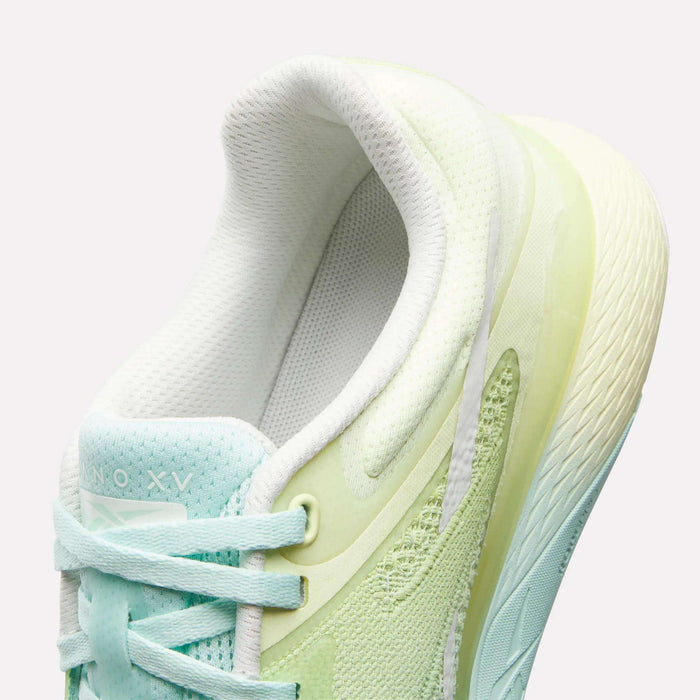 A close-up of the Reebok Women's Nano X5 Training Shoes shows pastel light green and aqua hues, white laces, a textured sole, and a padded collar for comfort. The inner lining and tongue are white.