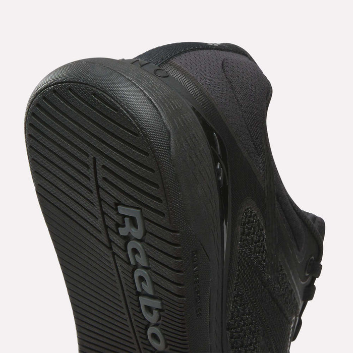 Close-up of the underside of Reebok Women's Nano X5 Training Shoes, highlighting the textured black rubber sole with Reebok branding and part of the mesh upper—crafted for women’s collections.