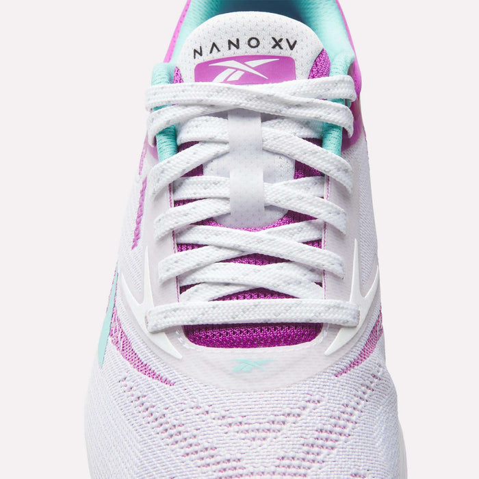 Close-up of the Reebok Women's Nano X5 Training Shoes in white with purple and teal accents, white laces, and "NANO XV" text on the tongue. The textured mesh design makes them ideal for women's athletic shoe collections.