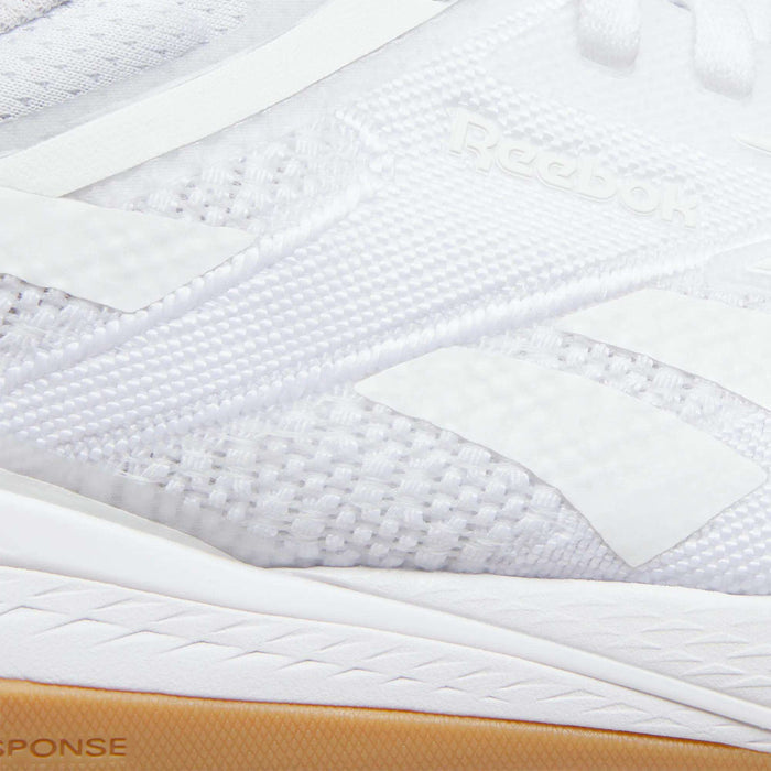 Close-up of Women's Nano X5 Training Shoes by Reebok, featuring textured mesh, white overlays, the Reebok logo, and a gum rubber sole—ideal for comfort in running or as iconic training footwear.