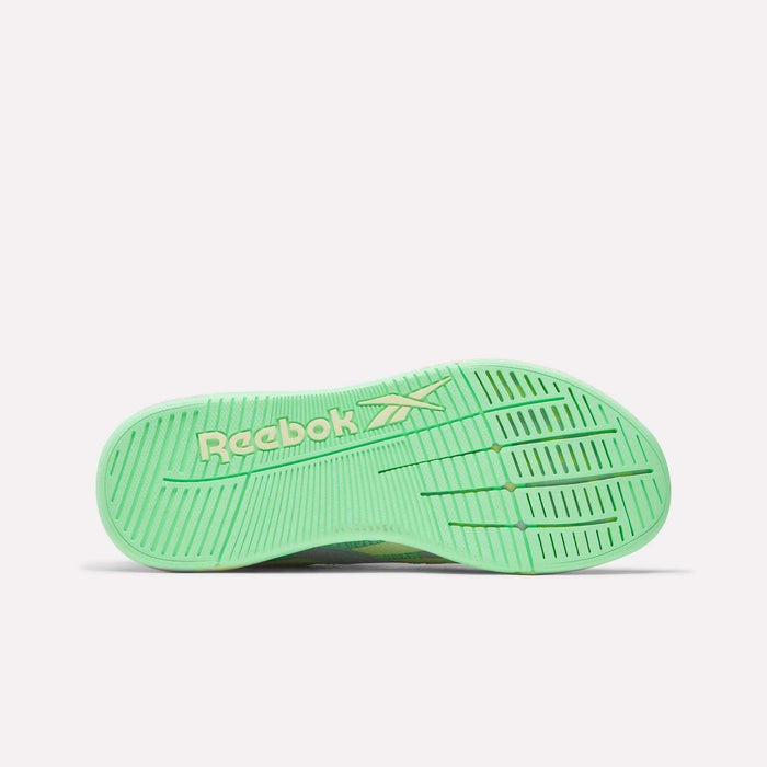 The image displays the bottom view of a green Women's Nano X5 Training Shoe by Reebok, showing a white Reebok logo and textured sole grooves for grip—an iconic addition to women’s training shoe collections.