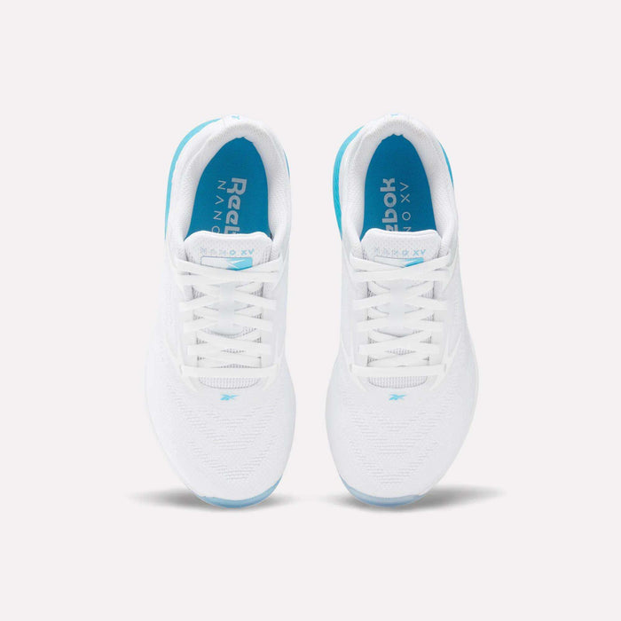Top view of Reebok Women's Nano X5 Training Shoes in white, with blue insoles and soles, white laces, and subtle blue accents. Shoes are placed side by side on a light background.