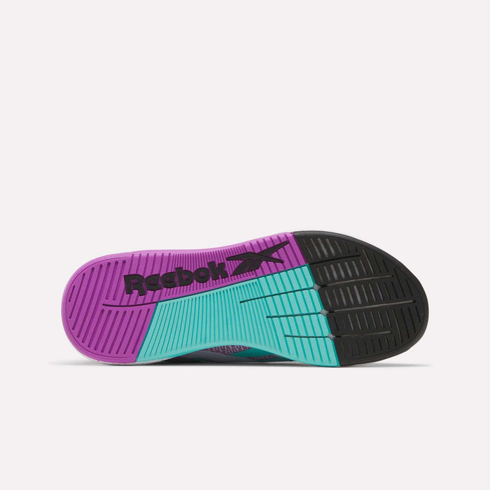 The Reebok Women's Nano X5 Training Shoes feature a comfortable fit and a colorful sole with purple on the left, teal in the middle, black on the right, plus a black Reebok logo and textured grip patterns for traction.