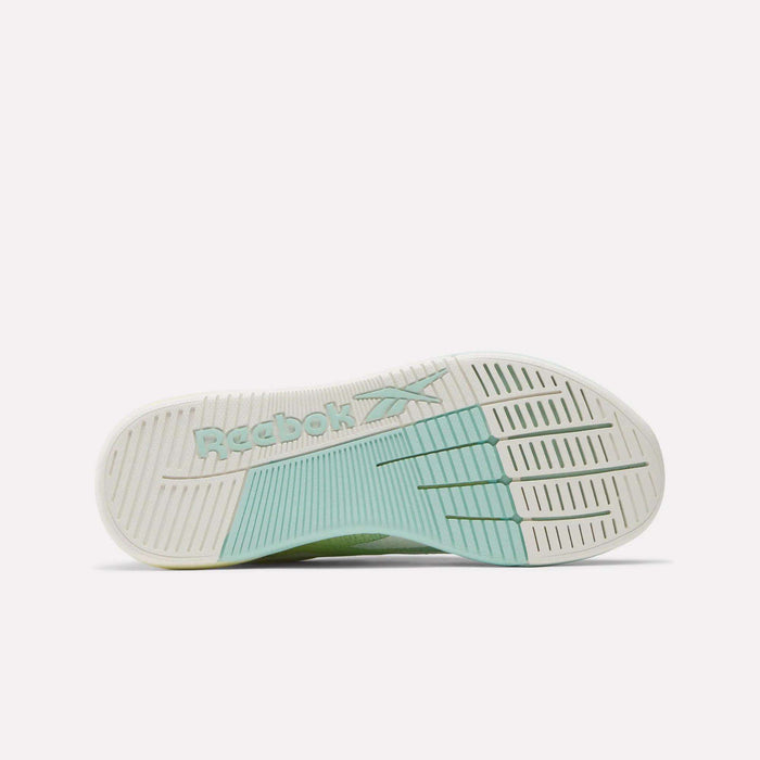 The image displays the sole of Reebok Women's Nano X5 Training Shoes, featuring a white and light green tread. The embossed green Reebok logo at the center adds a stylish touch, making these sneakers appealing for women.