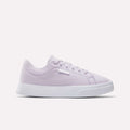 The Reebok Women's OnLux Court Lite Walking Shoes in light purple feature a white sole, white laces, and a small white brand tag. These comfortable sneakers are perfect for all-day wear and are shown on a plain white background.