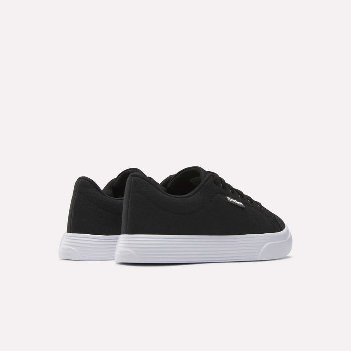 The Women's OnLux Court Lite Walking Shoes by Reebok are black low-top, comfortable walking shoes with white rubber soles, displayed from the back and side on a plain white background.