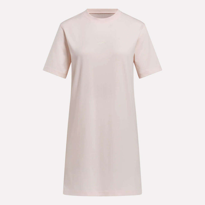 The Reebok Women's Oversized T-Shirt Dress is a light pink, short-sleeve, crew neck dress for women in a relaxed, casual fit, shown on a plain white background.