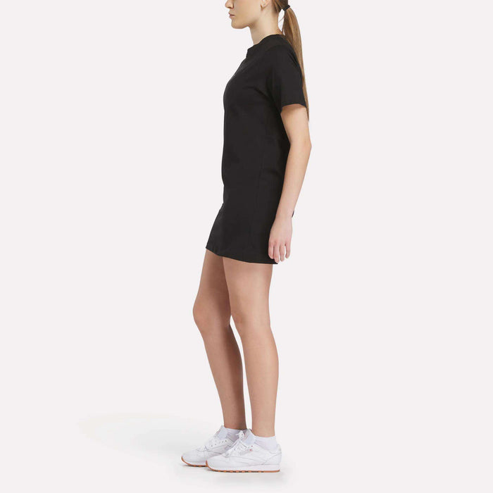 A woman in the Reebok Women's Oversized T-Shirt Dress showcases effortless style and comfort.