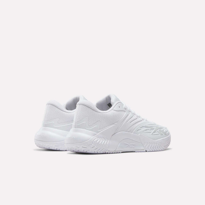 The Women's Phase Evo Tennis Shoes by Reebok feature an all-white design with textured soles and wavy side details, shown angled on a white background—ideal for everyday performance.