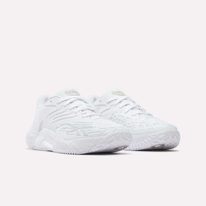A pair of Women's Phase Evo Tennis Shoes by Reebok in all white, featuring textured detailing and patterned soles, showcased on a plain light background.