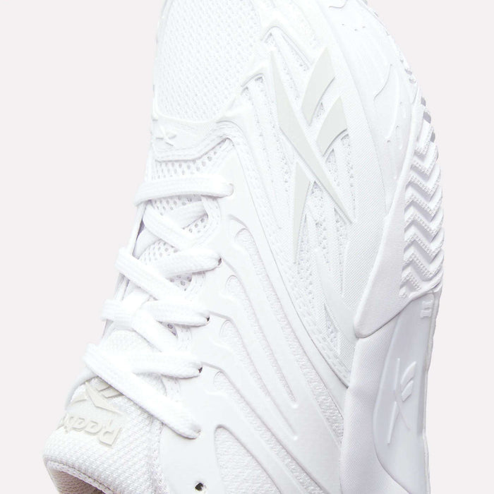 Close-up of Reebok Women's Phase Evo Tennis Shoes featuring textured mesh, detailed laces, and embossed logos on the side and tongue, set against a plain background.